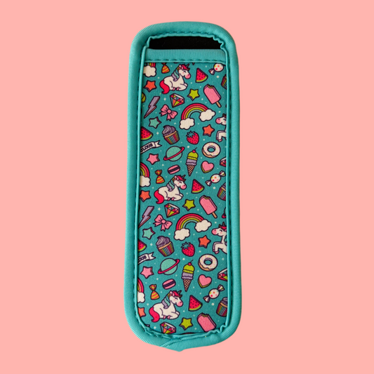 Bright teal icy pole holder sleeve featuring colourful cartoon-style prints of unicorns, rainbows, fruit, and sweets on a pink background.