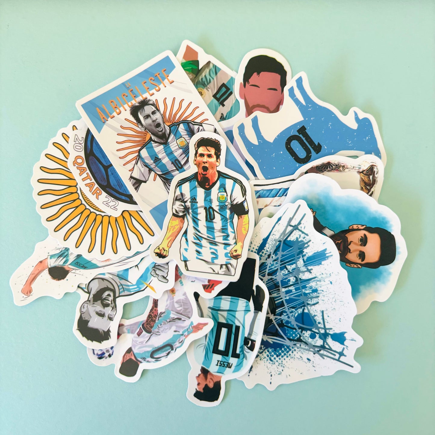 Pile of soccer-themed stickers featuring a player in blue-and-white stripes, goal scenes, and football graphics, displayed on a light teal background.