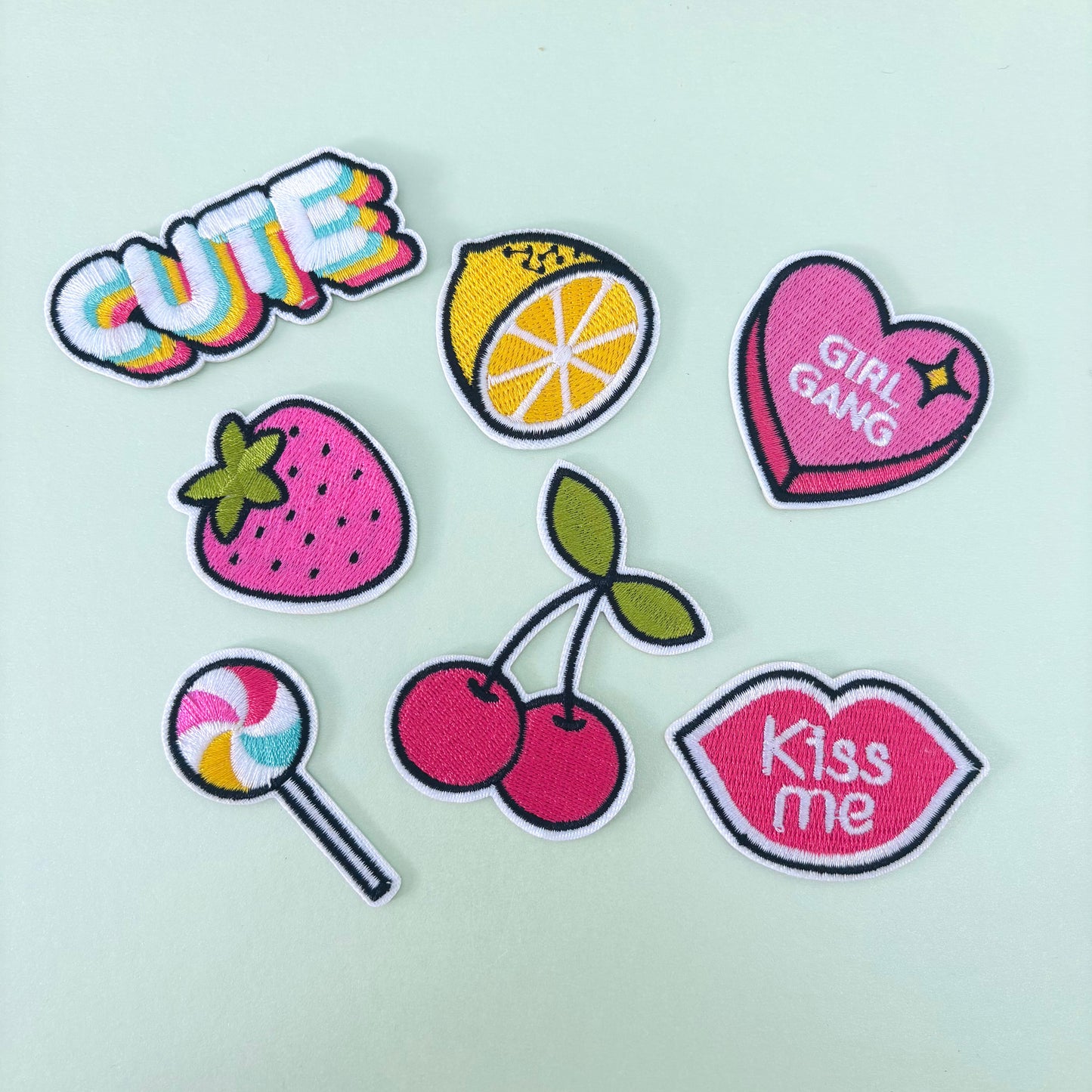 A collection of colorful embroidered patches with fruit designs and text, intended for iron-on application onto clothing.