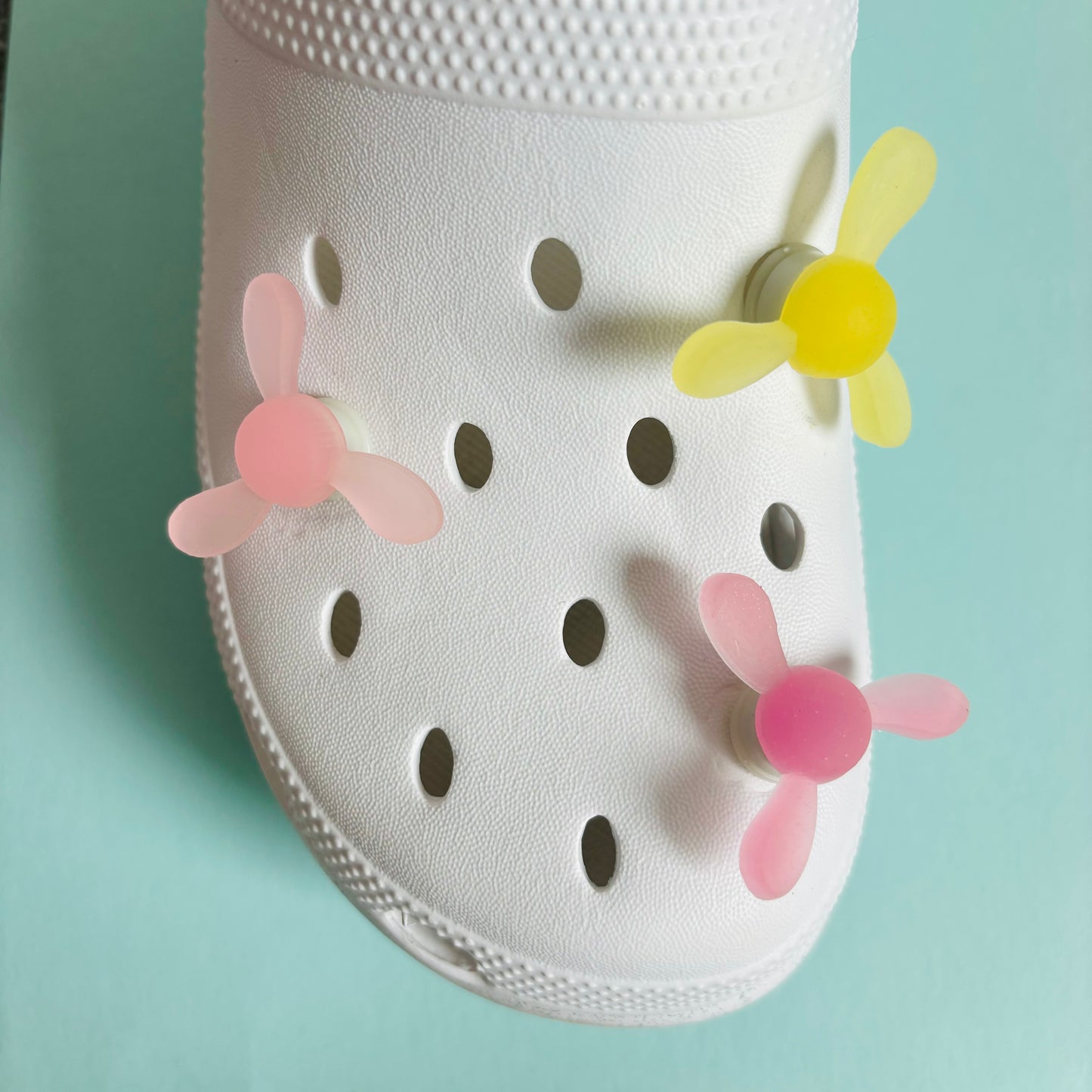 Colourful spinning charm designed to fit clog-style shoe holes, displayed on a neutral background.