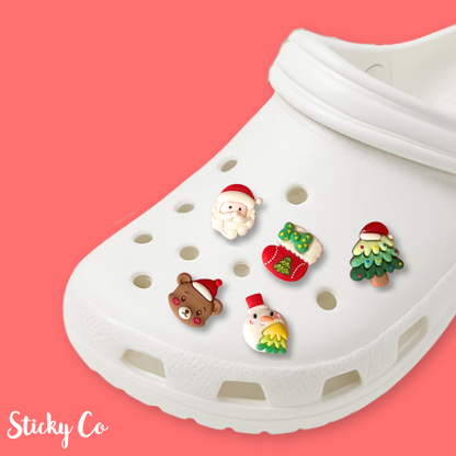 White clog with Christmas-themed shoe charms on a pink background