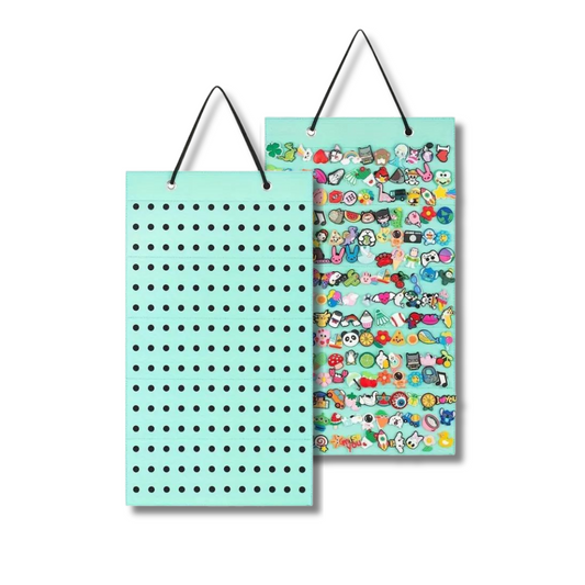 Mint green hanging display board with black perforated holes, shown empty and fully loaded with colourful clog charms and enamel pins.