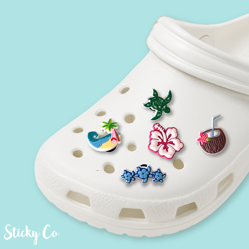 White clog shoe with colorful decorative charms on a light blue background