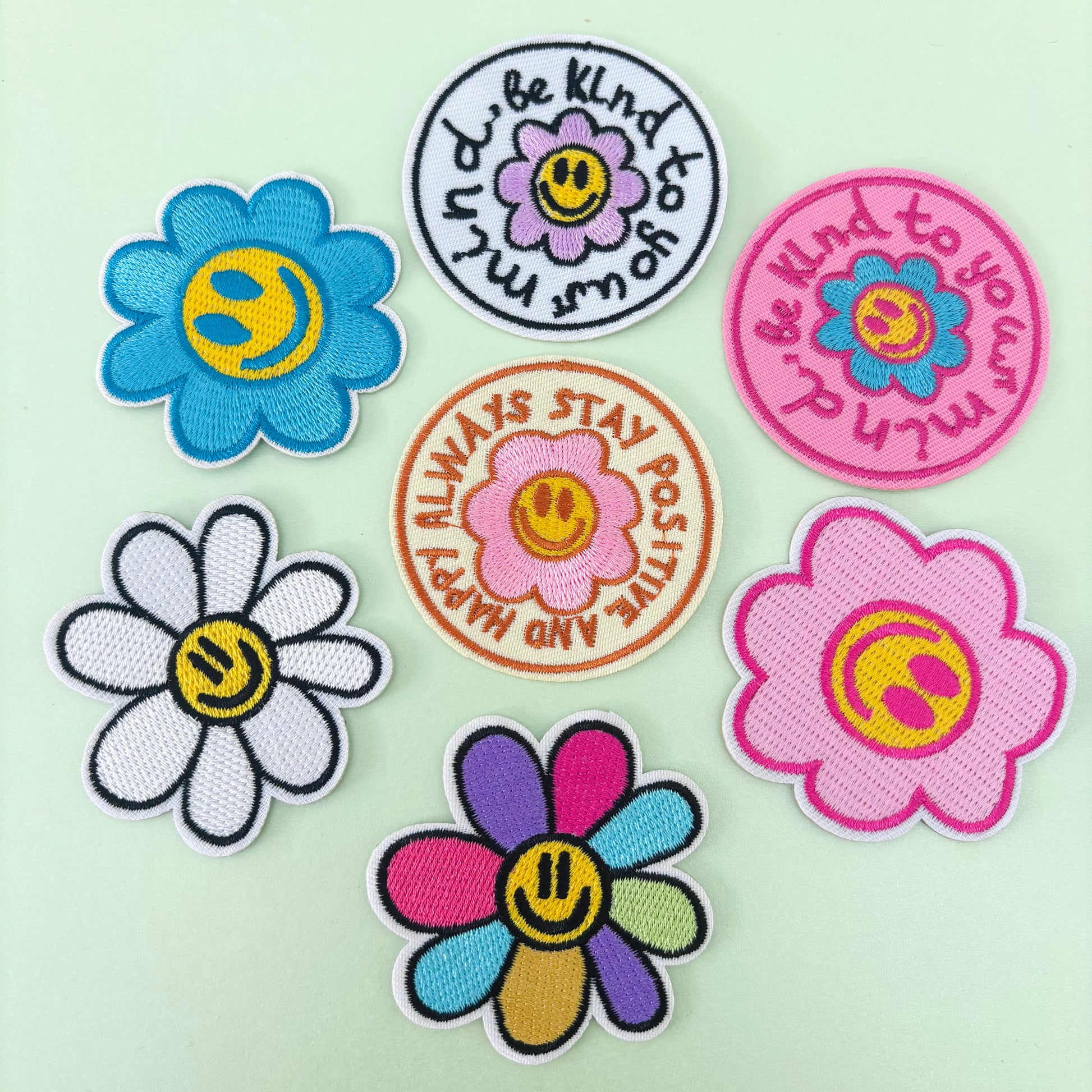 A collection of colorful embroidered flower patches with motivational slogans, designed for iron-on application.